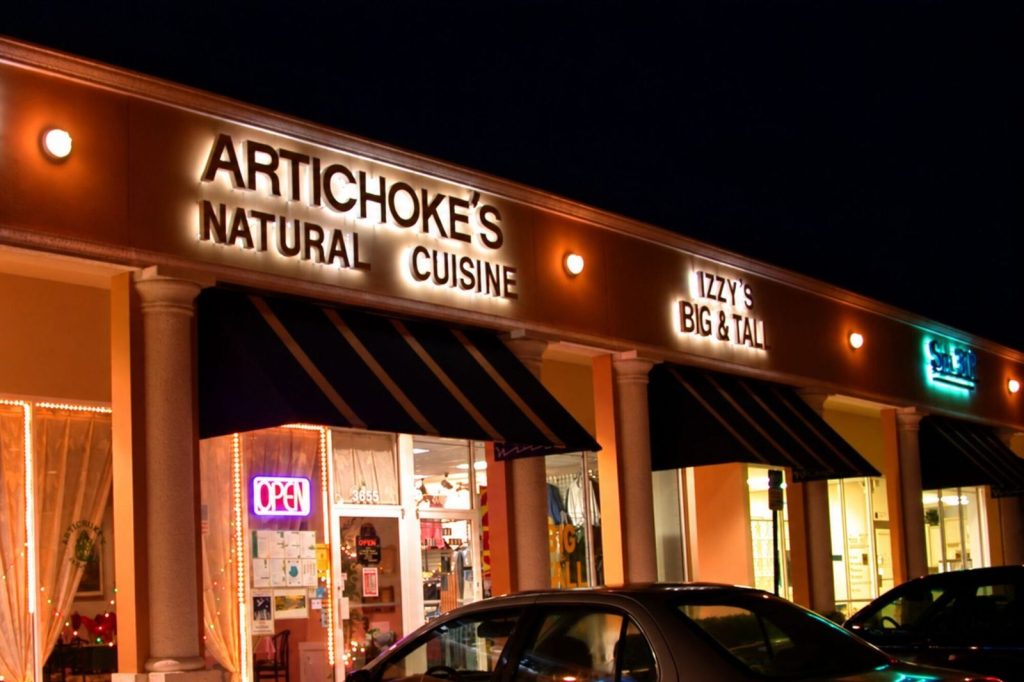 Artichoke's Natural Cuisine storefront at night with illuminated signs